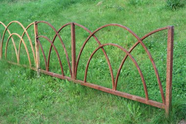 Parktaki eski paslı metal çit yeşil çimlerin arka planında