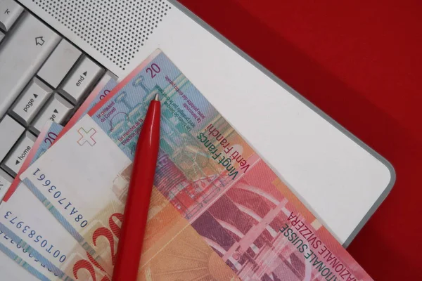 İsviçre banknotları ve gümüş dizüstü bilgisayarda kalem, serbest çalışan