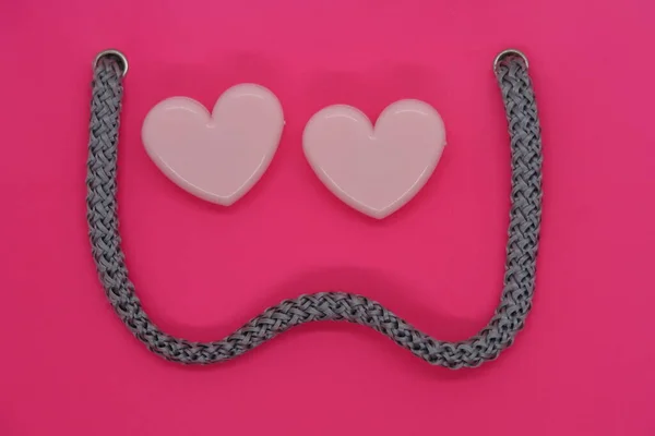 Two pink heart-shaped paper clips and vintage braided cord, memories, mood