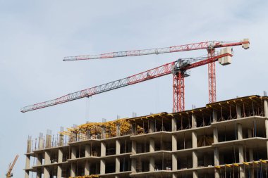 İki inşaat vinci ve inşaat halindeki bir yüksek bina.
