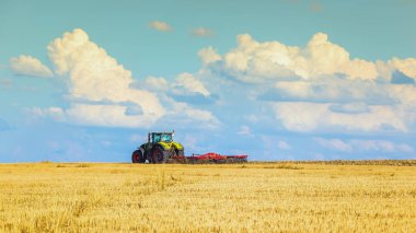 Yaz aylarında traktörün ısı alan hasat parlak güneşli gökyüzü bulutlu sonra pulluklar.