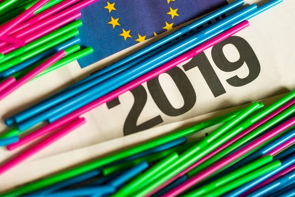 colorful plastic straws on news paper sheet with 2019 and EU sign on it. ban act of plastic packaging in Europe 2019