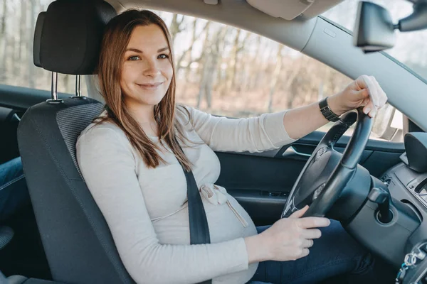 Mooie jonge zwangere vrouw zitten in de auto. Veiligheid aandrijfconcept. — Stockfoto