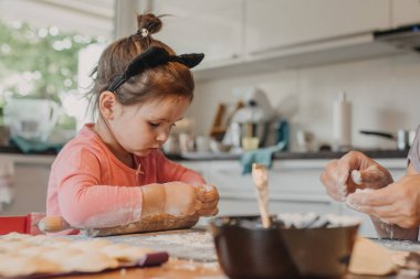yürümeye başlayan çocuk kız hamur pirogi için onun büyükannesi ile mutfakta ev tarafından rulo