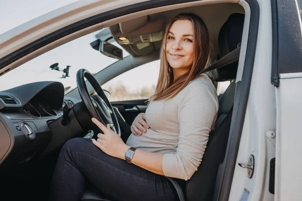 Bela jovem grávida sentada no carro. Conceito de acionamento de segurança — Fotografia de Stock