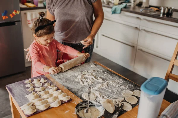 Kleinkind rollt Teig für Pirogi mit Großmutter in der Küche am Haus — Stockfoto