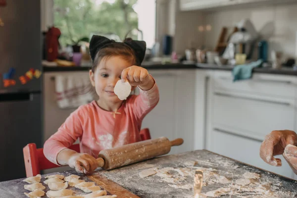 Kleinkind rollt Teig für Pirogi mit Großmutter in der Küche am Haus — Stockfoto