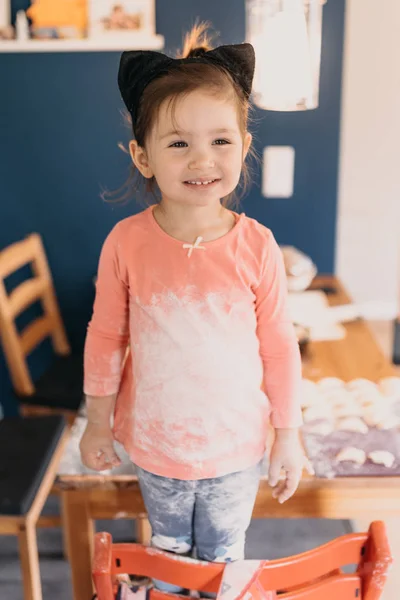 Una niña está de pie en la cocina con ropa sucia de harina —  Fotos de Stock