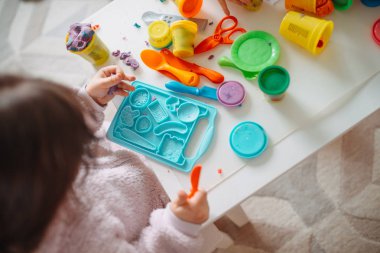 İki küçük kız çocuk odasında hamurla oynuyorlar.