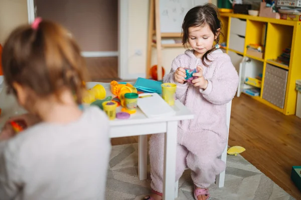 Duas meninas brincam no berçário com massa de brincar — Fotografia de Stock