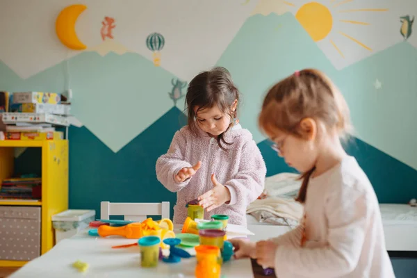 Zwei kleine Mädchen spielen im Kinderzimmer mit Spielteig — Stockfoto