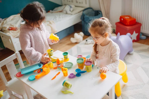 Zwei kleine Mädchen spielen im Kinderzimmer mit Spielteig — Stockfoto