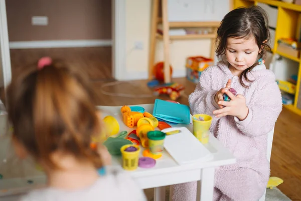 Duas meninas brincam no berçário com massa de brincar — Fotografia de Stock