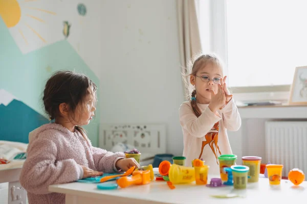 Zwei kleine Mädchen spielen im Kinderzimmer mit Spielteig — Stockfoto