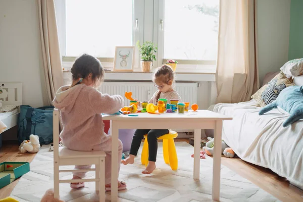 İki küçük kız çocuk odasında hamurla oynuyorlar. — Stok fotoğraf