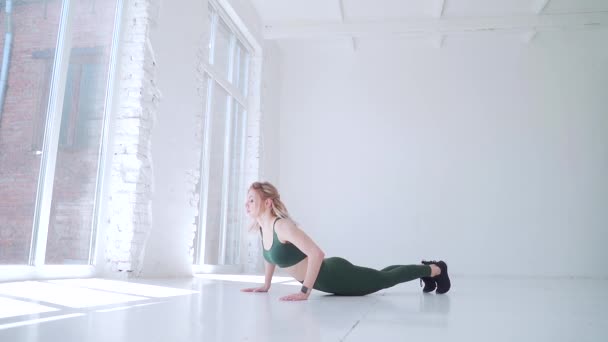 매력적 소녀가 점프로 쪼그려 앉는다 조련사는 홀이나 스튜디오에서 운동을 여자는 — 비디오