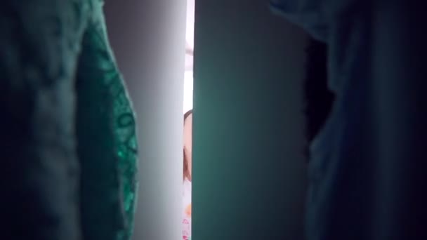 パジャマの少女は服を選ぶために朝クローゼットのドアを開ける 真ん中からの眺め 子供用の寝室のワードローブは — ストック動画