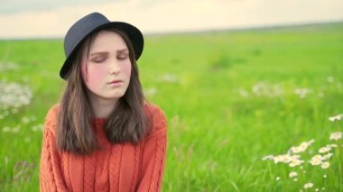 Çimlerin üzerinde oturan şapkalı ve kazaklı genç bir taşra kızının portresi. Çilleri ve kırmızı yanakları olan genç bir kız. Yeşil gözler ve çenede bir delik.