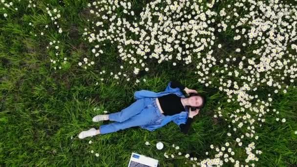 Joven Hipster Chica Acostada Césped Entre Las Flores Escucha Música — Vídeo de stock