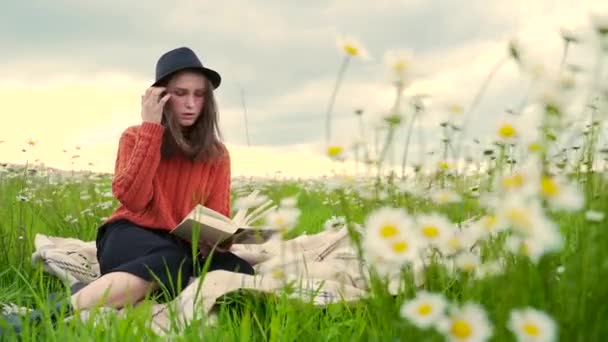 Νεαρή Ελκυστική Μαθήτρια Που Κάθεται Στο Γρασίδι Ανάμεσα Στα Λουλούδια — Αρχείο Βίντεο