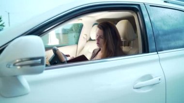  Direksiyon başında elinde defterle oturan bir kadın yöneticinin portresi. Lüks beyaz arabalı kadın iş kadını. Komisyoncu çalışır ve veri yazar..