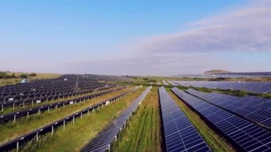  Büyük bir alan güneş panelleriyle kaplıdır. Güneş, güneş panellerinden yansıyor. Ufuk. Üst hava manzaralı. Yeşil alan. Çimen ve doğa. Kırsal kesimde. Güneş çiftliği. modern yenilenebilir enerji