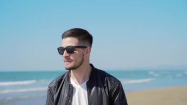  Siyah deri ceketli, güneş gözlüklü, kendine güvenen şık bir adamın portresi. Kız koşar ve arkasından boynuna atlar. Mutlu mutlu bir çift. Birlikte iyi eğlenceler. Kız arkadaşım beni sırtımda taşıyor.