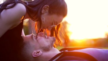 Gün batımında bir öpücüğe yaklaş. Çimlerde yatan çekici bir çift.. 