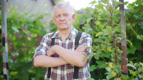 Portret van een oudere man in de natuur in de tuin vol vertrouwen kijkend naar een camera — Stockvideo