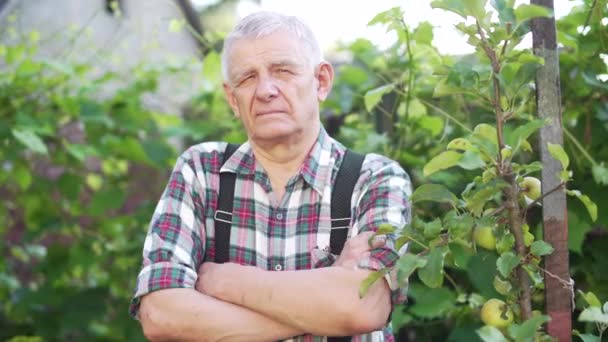 Retrato de un hombre mayor en la naturaleza en el jardín mirando con confianza una cámara — Vídeo de stock