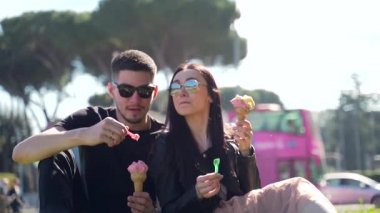 Bahçedeki parkta oturan iki genç turistin portresi. Dondurma ye.