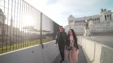  Adamın elini turist kız tutuyor. Gün batımında ya da gün doğumunda mutlu bir gülümseme. Vittoriano, Piazza Venezia 'nın arka planında el ele tutuşan şık turistler. Siyah deri ceketli hippiler. 