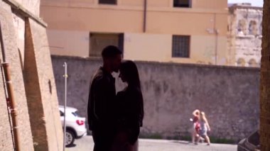 Caddedeki bir binanın kemerinde el ele tutuşup kucaklaşan şık, genç bir çift hippinin silüeti. Kız ve erkek şehir geçmişinde tanışırlar. Aşık turistler kendilerini iyi hissederler. Yavaş çekim