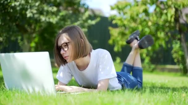 Молодая Женщина Лежит Лужайке Ноутбуком Студентка Парке Траве Работает Учится — стоковое видео