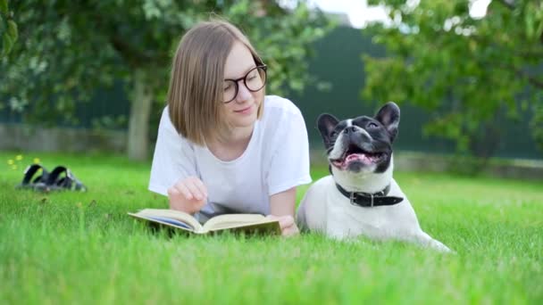 Vidám Diák Könyvet Olvas Parkban Ülve Aztán Megveregeti Imádnivaló Kiskutyáját — Stock videók