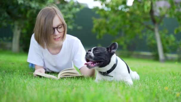 Веселый Студент Читает Книгу Сидя Парке Затем Гладит Очаровательного Щенка — стоковое видео