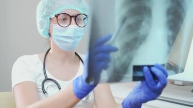 Genç bir doktor akciğerlerin fotoğrafını silecek. Zatürree veya tüberküloz teşhisi. Hastanın röntgen incelemesi. Önleme, akciğer kanseri, zatürree ve tüberküloz