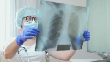 Masada oturan kadın doktor, bilgisayarla çalışıyor, akciğerlerinin röntgenini çekiyor, florografi çekiyor, hastanedeki hafif ofiste röntgen çekiyor. Tıbbi önlüklü bir kadın, danışma odasında steteskop. Tıp konsepti