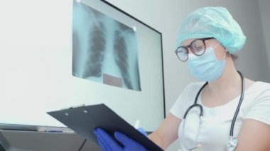 Genç bir doktor akciğerlerin fotoğrafını silecek. Zatürree veya tüberküloz teşhisi. Hastanın röntgen incelemesi. Önleme, akciğer kanseri, zatürree ve tüberküloz