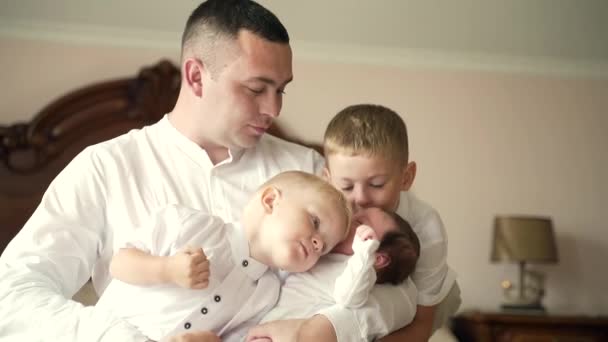 幼い白人の父親の肖像画彼の腕の中で新生児の娘を保持します 抱擁し 彼女にキス 二人の男の子を抱えている女の子を持つ幸せな男 子供たちと一緒に 父の日 — ストック動画