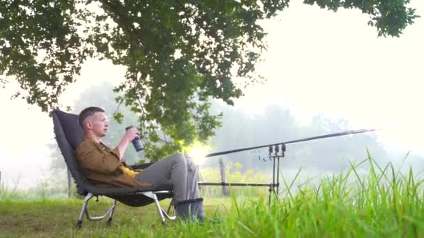 Young Stylish Fisherman Guy Sitting Fishing Chair Drinking Drink Tea — Stock Video