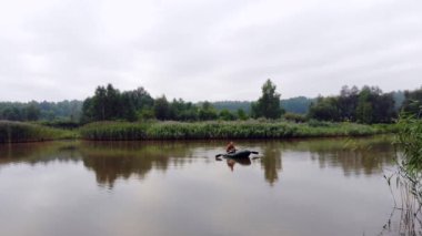 Genç, şık hippi balıkçı sazlıklar arasında bir gölde ya da nehirde yelken açar. Genç bir adam şişme bir teknede kürek çekiyor. Doğada rahatlar. Suyun kenarında kamp yapmak. Rekreasyon