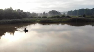 Genç, şık hippi balıkçı sazlıklar arasında bir gölde ya da nehirde yelken açar. Genç bir adam şişme bir teknede kürek çekiyor. Doğada rahatlar. Suyun kenarında kamp yapmak. Rekreasyon