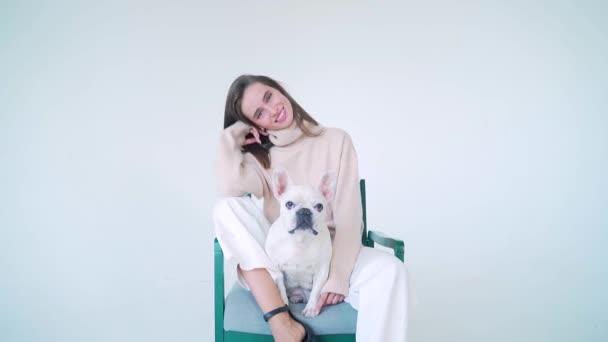 Doamnă Tânără Veselă Pulover Tricotat Pantaloni Albi Stând Scaun Buldogul — Videoclip de stoc