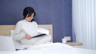 Genç hasta iş kadını yöneticisi hastalık sırasında evde, yatakta çalışıyor. Beyaz pijamalı ya da takım elbiseli bir kadın sabahları elinde laptop ve belgelerle kanepede çalışıyor. Yatak odasında iş kadını