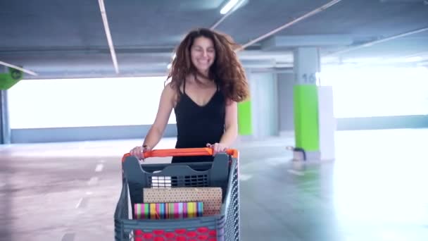 Wanita Bahagia Dengan Rambut Hitam Mendorong Troli Belanja Penuh Kantong — Stok Video