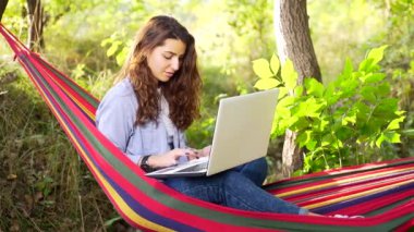 Genç Yetişkin Kadın Serbest Çalışan Hamakta Doğa Üzerine Dizüstü Bilgisayarla Çalışıyor. Çevrimiçi Uzaktan Çalışan Hippi Öğrenci Kız Ormanda Bir Yaz Günü Ya da Kamp Yapıyor. Kadın İş Dinlenme ve Rahatlama 