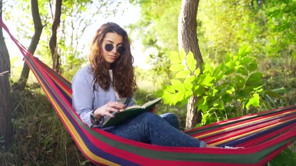 Yaz Parkındaki Renkli Hamakta Uzanmış Siyah Saçlı Yeni Kitap Okuyan — Stok video