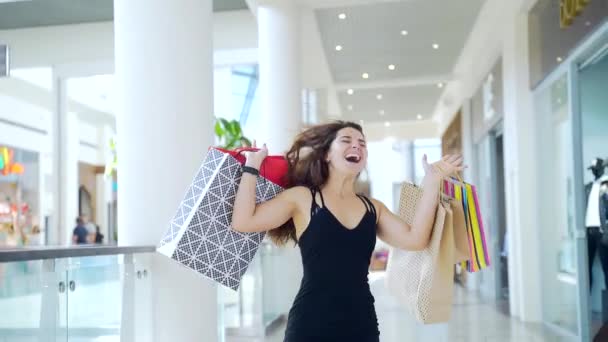 Jovem Encantadora Com Cabelo Escuro Pulando Alegria Com Sacos Coloridos — Vídeo de Stock