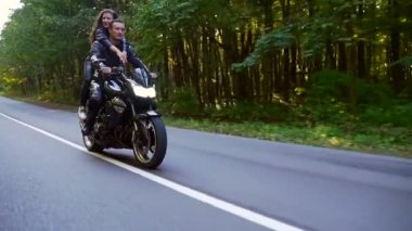  Genç çift ormanda motosiklet sürüyor.